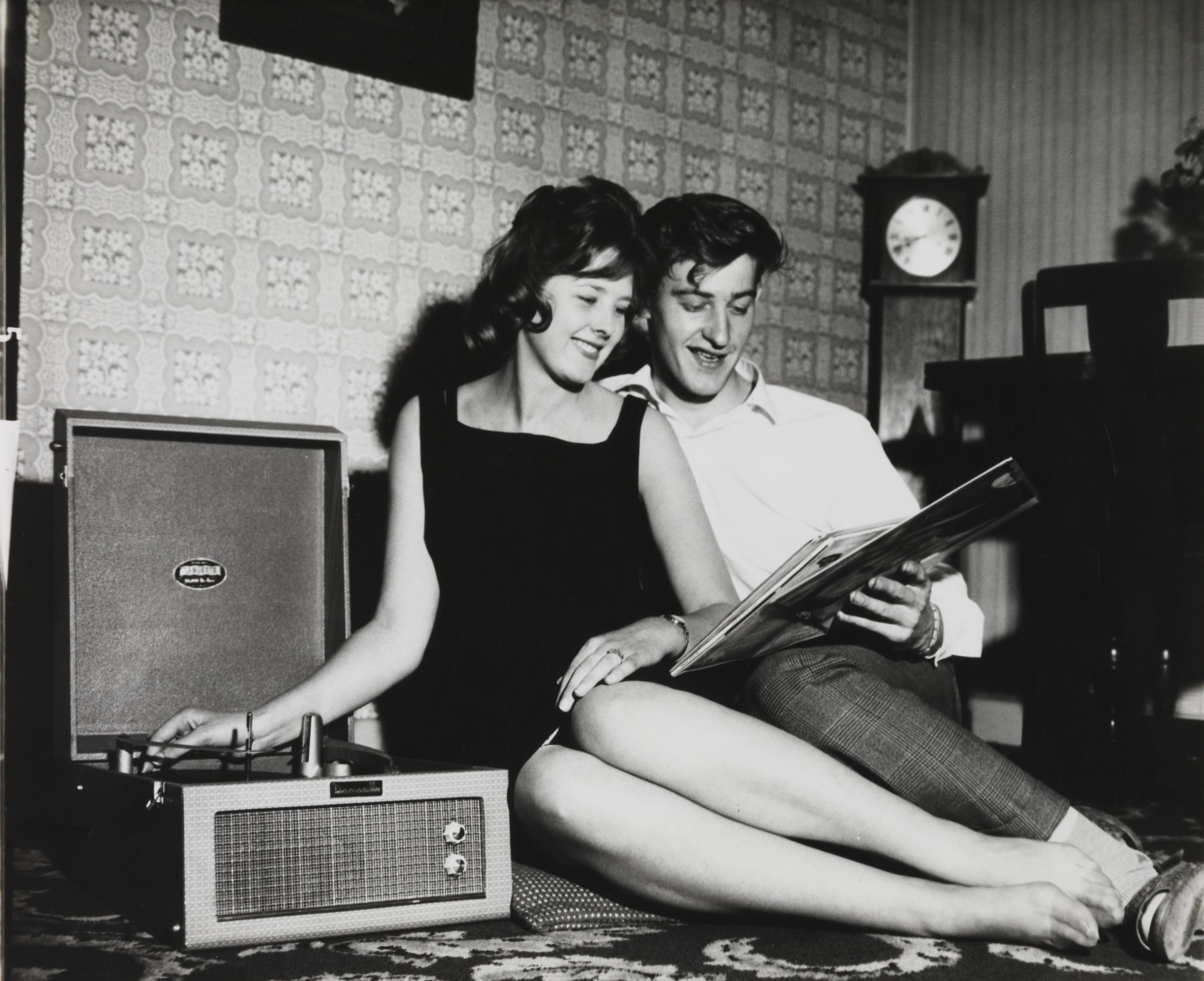 Young couple listening to music and looking at records in a living room