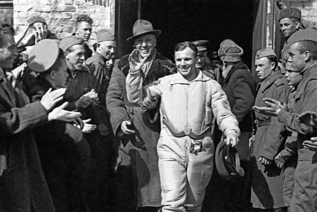 A smiling Yuri Gagarin waves at cheering crowds soon after his landing.