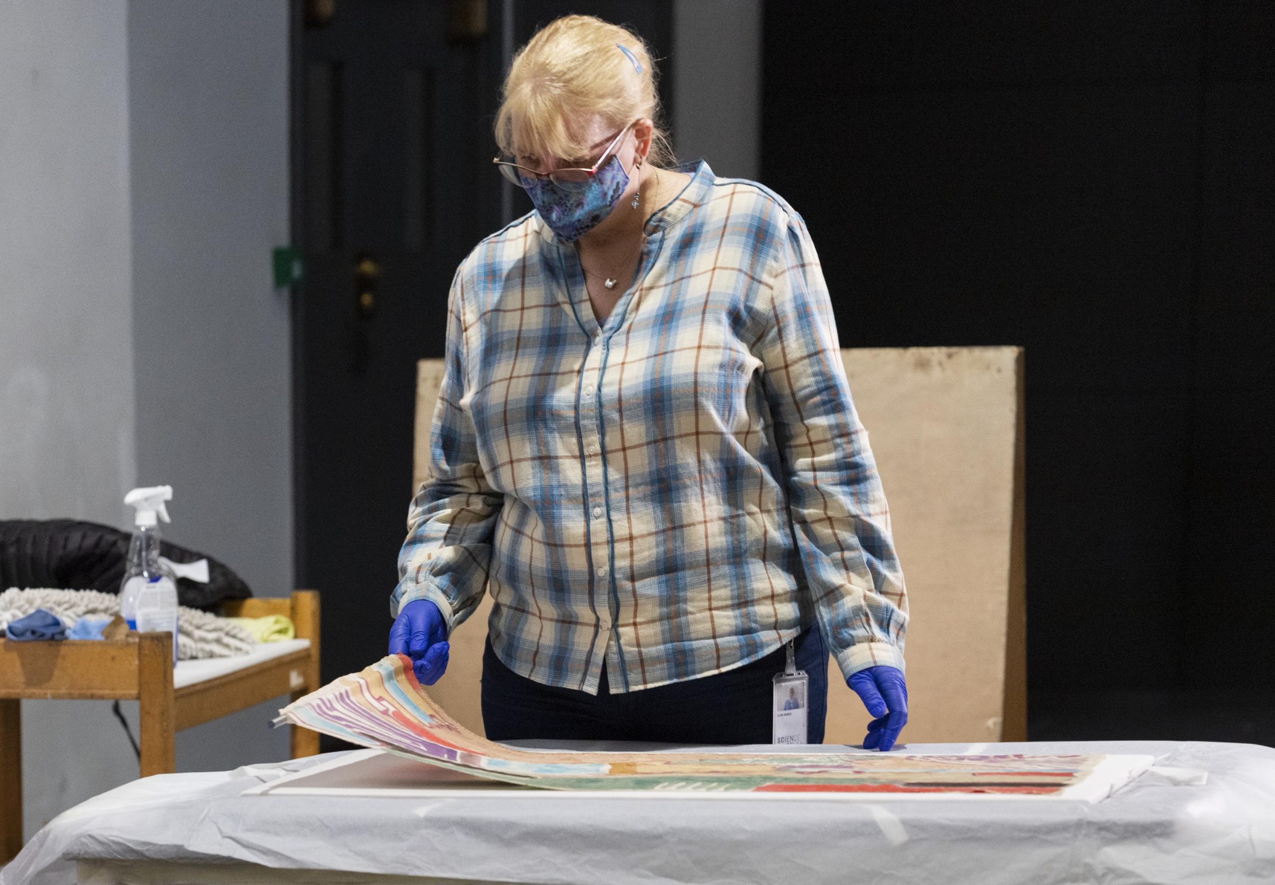 Conservator Kate prepares to install the painted silk item in its new display at the Science Museum.