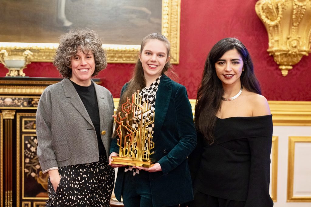 Competition winner Hannah Goldsmith holding her winning trophy with Create the Trophy competition judges Zoe Laughlin and Rebeca Ramos at the 2021 QEPrize presentation