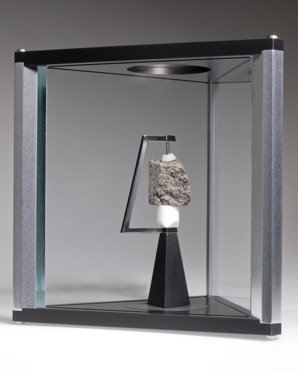 A piece of Moon rock held between pincers in a triangular container. 