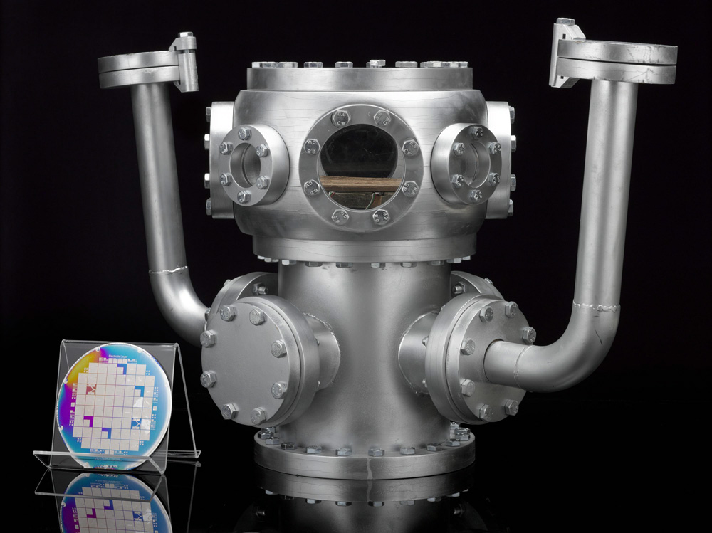 Group shot of L2018-1. Model of the vacuum chamber - part of a prototype quantum computer, and power supply and L2018-2 Quantum computing microchip wafer. © Ion Quantum Technology group at the university of Sussex and collaborators.