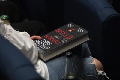 An audience member holds The Apollo Murders on their lap.