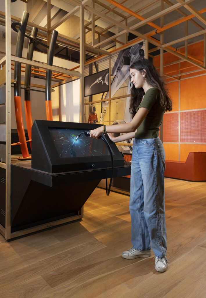 A visitor tries out their welding skills in Technicians: The David Sainsbury Gallery.